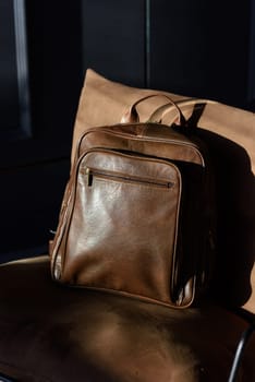 Brown leather backpack on chair, close up..