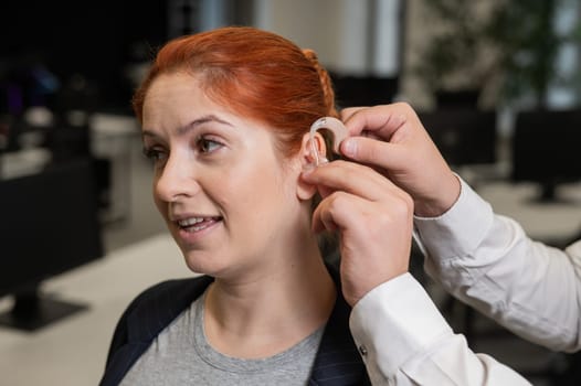 Man putting hearing aid on Caucasian red-haired woman