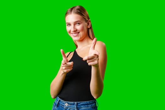 Young Woman Pointing at Something against green background in studio