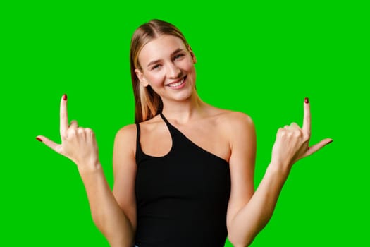 Young Woman Pointing Up Against Green Background in Studio