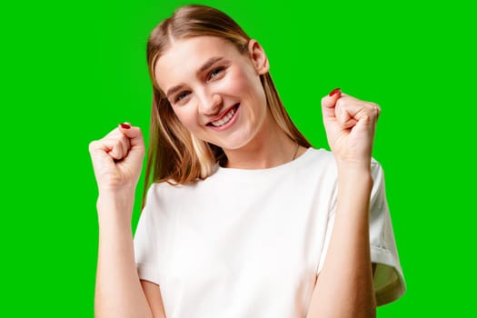 Happy Young Woman Raising Fists against green background in studio