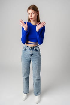 Young Woman in Blue Top Holding Out Hands in studio