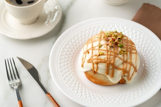 Cinnamon roll bun with icing on plate close up