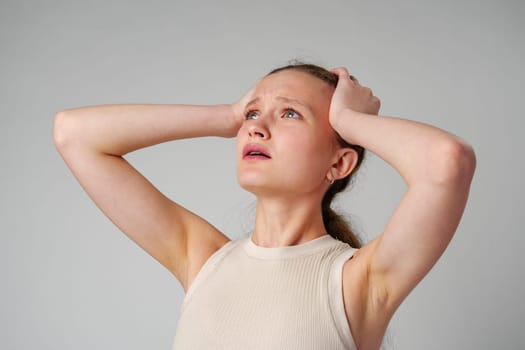 Young Woman Holding Head in Hands in studio close up