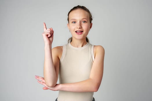 Young Woman Gesturing With One Finger Up Against a Grey Backdrop in studio