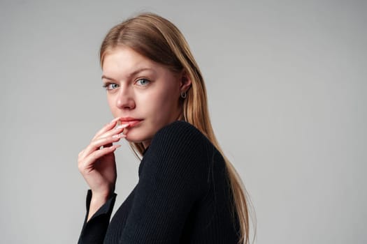 Young Woman In Black Shirt Expressing Discontent Against Grey Background close up