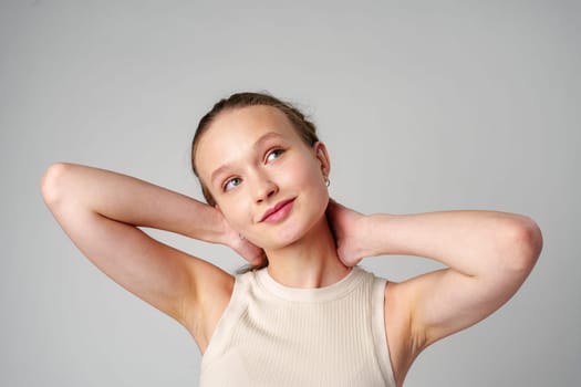 Girl in Beige Tank Top and Grey Jeans on gray background in studio