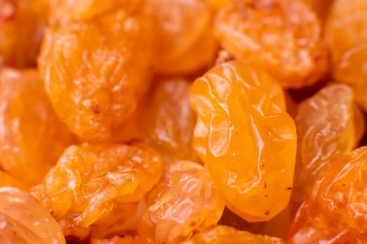 Golden-colored raisins lie in a pile, close-up of raisin texture, macro shot.