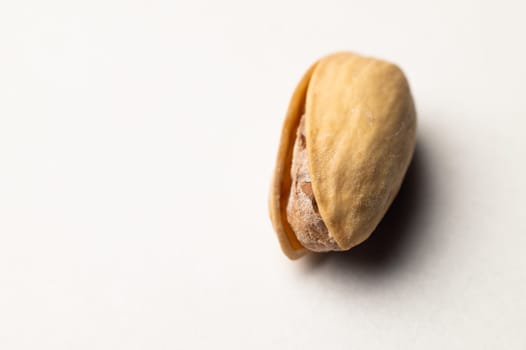 One pistachio nut on a white background, close-up.