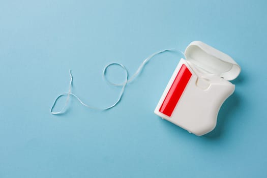 Top view of dental floss in white box on blue background