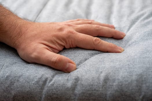 The man checks the quality and softness of the new mattress he will buy by pressing it with his hand