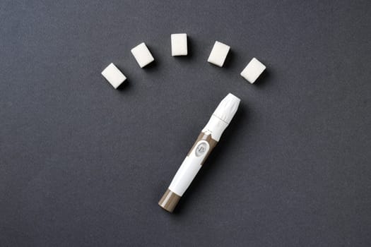 Blood sugar level displayed with sugar cubes and a lancet pen on a dark background