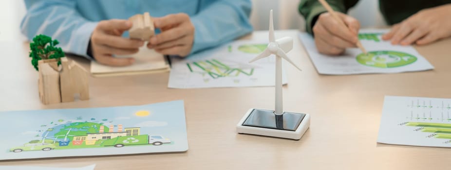 Business people invest in green business plan at meeting room on table with house model and wind mill placed represented eco house and renewable energy. Closeup. Delineation.