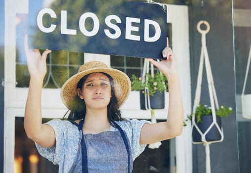 Closed, floral and woman with sign, recession and inflation with bankruptcy, unemployment or failure. Person, entrepreneur or worker with poster, stagflation or stress with store, emotion or business.