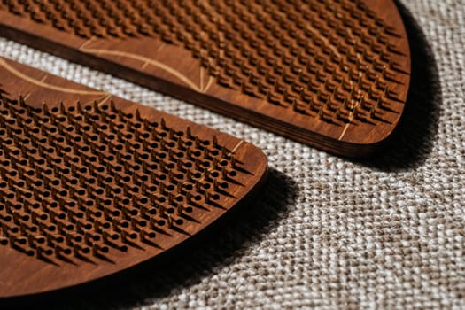 Wooden sadhu boards with symmetrical peg designs for acupressure therapy, set on a textured mat.