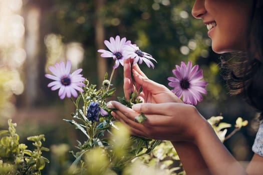 Closeup, flowers and woman with plants in nursery, smelling and sunshine with smile, spring and nature. Person, outdoor and girl in garden, florist and happy with summer, growth and sustainability.