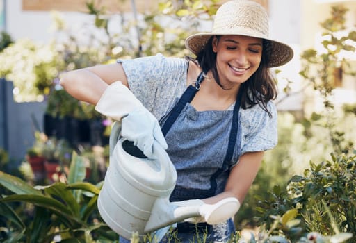 Woman, watering can and smile with plants for gardening at work in outside with nature in spring. Happiness, business and florist with passion, water and shop with service for floral growth for eco.