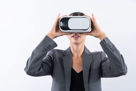 Caucasian female leader using visual reality while holding VR goggle. Professional businesswoman wearing visual reality headset while standing at white background to connect metaverse. Contraption.