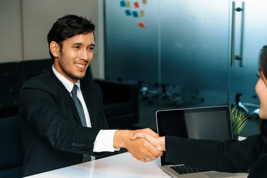 Business people agreement concept. Businessman and Asian businesswoman do handshake in the office. uds