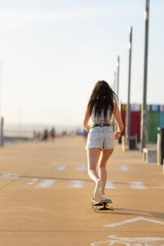 A woman is skateboarding down a sidewalk. She is wearing shorts and a white shirt. The scene is sunny and bright
