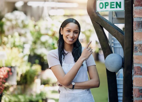 Happy woman, portrait and open sign at nursery with small business, gardening and sustainability with welcome. Pointing at poster, notice with flower seller or florist, entrepreneur and service.