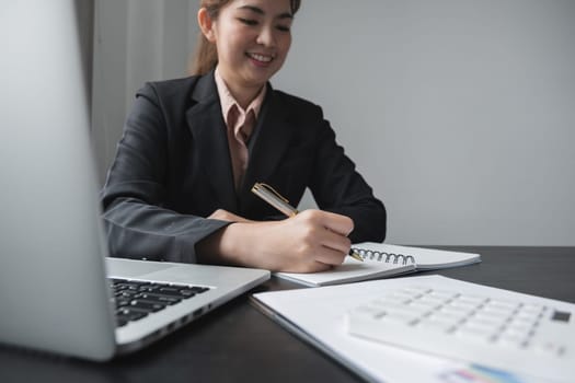 businesswoman writing making list taking notes in notepad working or learning online with laptop at office.