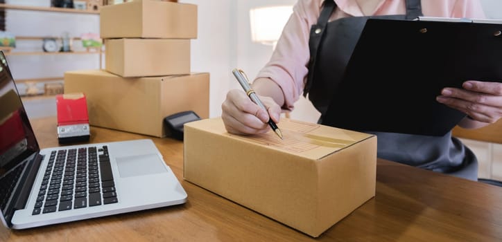 Business From Home Asian woman preparing package delivery box Shipping for shopping online. young start up small business owner at home online order.