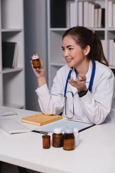 A woman doctor is sitting at a desk with a bottle of medicine in her hand. She is smiling and she is happy