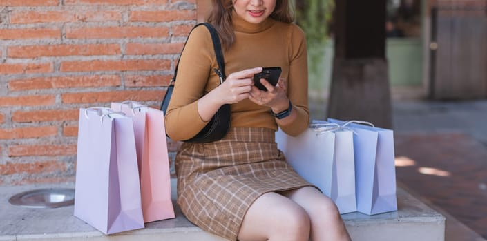 A woman sitting on a bench with a cell phone in her hand.