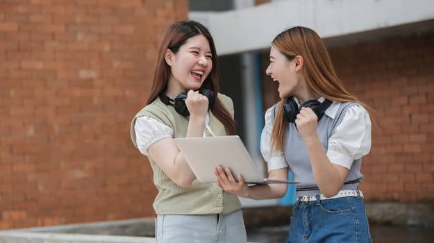 Beautiful young Asian woman college student with friends at outdoors. College student working on the college campus.