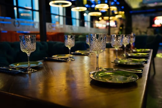 A table with a number of wine glasses and plates. The table is set for a meal. Scene is elegant and sophisticated