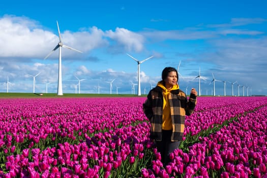 A mesmerizing scene unfolds as an Asian woman stands surrounded by a vast field of vibrant purple tulips in the Netherlands during Spring.