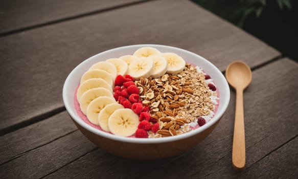 Colorful smoothie bowl in a coconut shell, topped with banana, goji berries, granola, and coconut flakes.