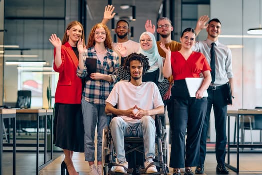 A diverse group of young business people walking a corridor in the glass-enclosed office of a modern startup, including a person in a wheelchair and a woman wearing a hijab.