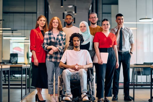 A diverse group of young business people walking a corridor in the glass-enclosed office of a modern startup, including a person in a wheelchair and a woman wearing a hijab.