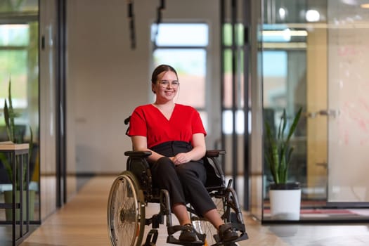 A modern young businesswoman in a wheelchair is surrounded by an inclusive workspace with glass-walled offices, embodying determination and innovation in the business world.