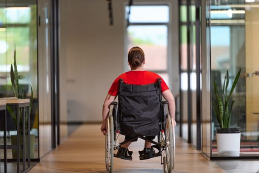 A modern young businesswoman in a wheelchair is surrounded by an inclusive workspace with glass-walled offices, embodying determination and innovation in the business world.