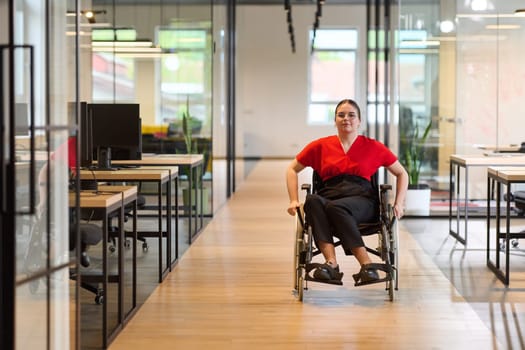 A modern young businesswoman in a wheelchair is surrounded by an inclusive workspace with glass-walled offices, embodying determination and innovation in the business world.