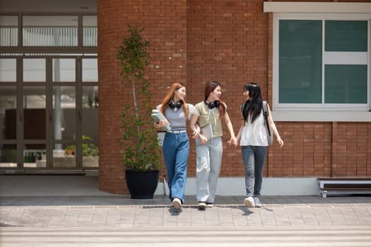 College friends walk to class together. University student in campus talk and have fun outdoors.