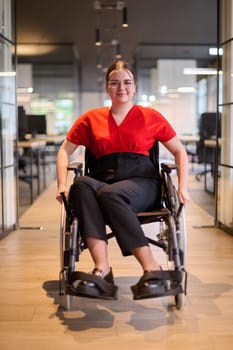 A modern young businesswoman in a wheelchair is surrounded by an inclusive workspace with glass-walled offices, embodying determination and innovation in the business world.