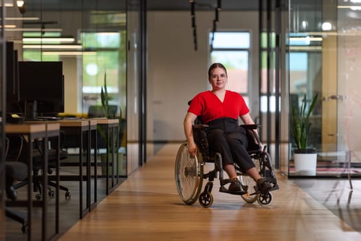 A modern young businesswoman in a wheelchair is surrounded by an inclusive workspace with glass-walled offices, embodying determination and innovation in the business world.