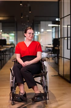 A modern young businesswoman in a wheelchair is surrounded by an inclusive workspace with glass-walled offices, embodying determination and innovation in the business world.