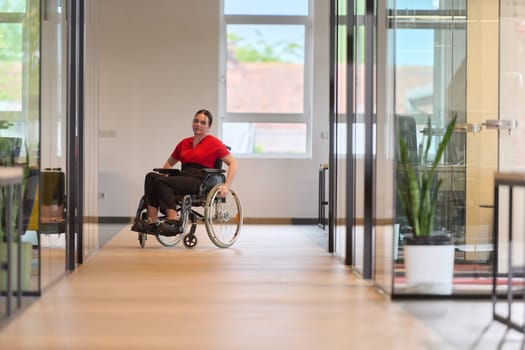 A modern young businesswoman in a wheelchair is surrounded by an inclusive workspace with glass-walled offices, embodying determination and innovation in the business world.