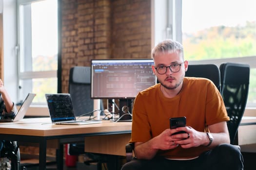 A diverse group of business professionals collaborates in a modern startup coworking center, utilizing a mix of paper-based and technological tools such as mobile phones and computers to collectively.