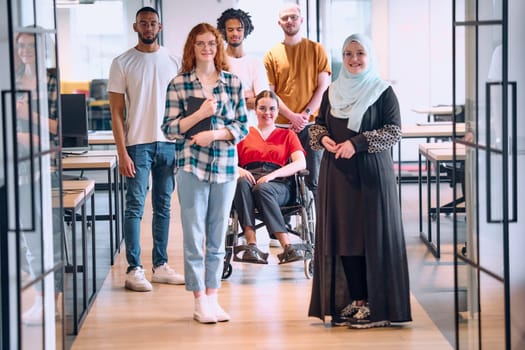 people walking a corridor in the glass-enclosed office of a modern startup, including a person in a wheelchair and a woman wearing a hijab.