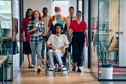 A diverse group of young business people congregates within a modern startup's glass-enclosed office, featuring inclusivity with a person in a wheelchair, an African American young man, and a hijab muslim woman