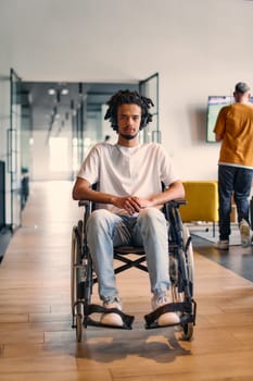 An African-American young entrepreneur in a wheelchair is surrounded by his business colleagues in a modern office setting, embodying diversity and collaboration in the workplace.