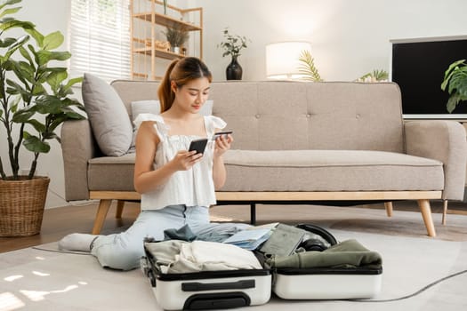 Young Asian tourist packs her suitcase, checks her belongings and passport in preparation for her weekend trip.