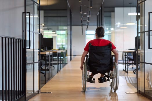 A modern young businesswoman in a wheelchair is surrounded by an inclusive workspace with glass-walled offices, embodying determination and innovation in the business world.