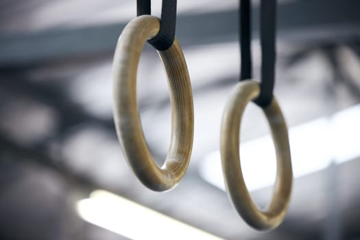 Gymnastic rings, gym and workout for aerobics, fitness and strong or power challenge for training. Equipment, tool and flexibility exercise or sports for wellness, arena and gear for competition.